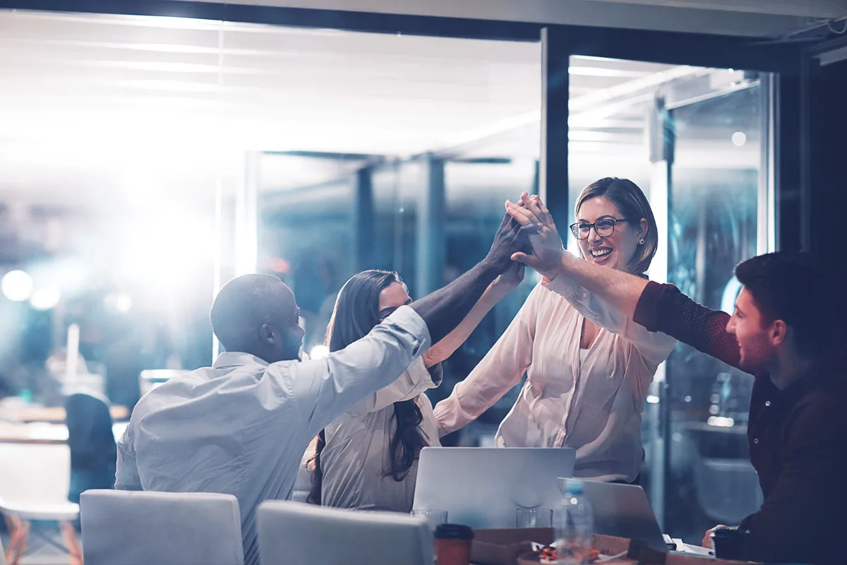 Business team high-fiving in a conference room