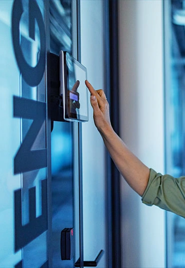 A woman typing a code into a tablet mounted on an office wall