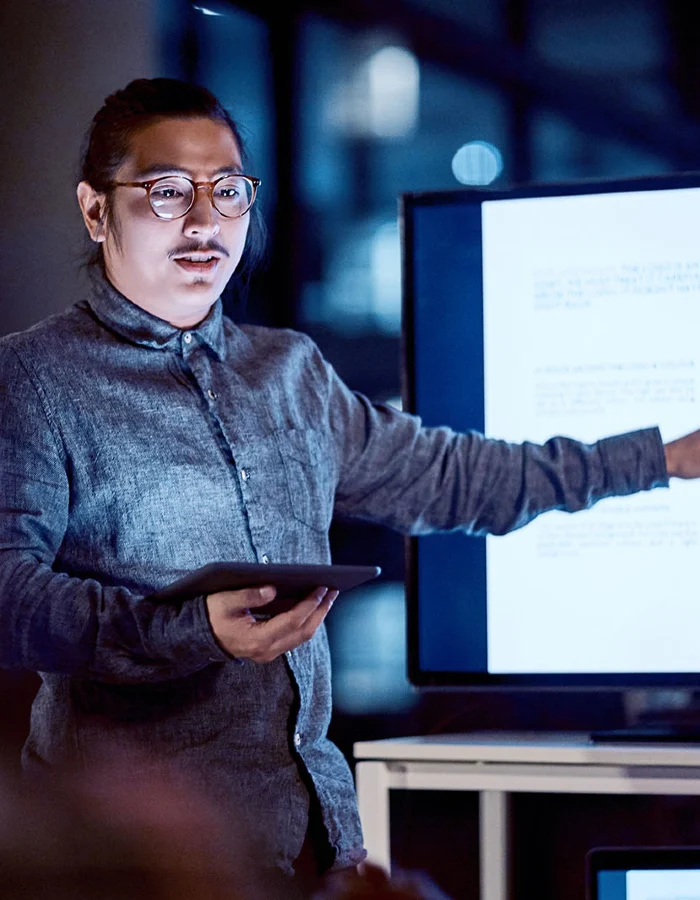 A young tech professional addressing with a tablet addressing a team