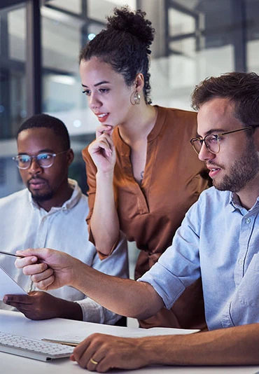 A woman helping two men at a computer in a training session