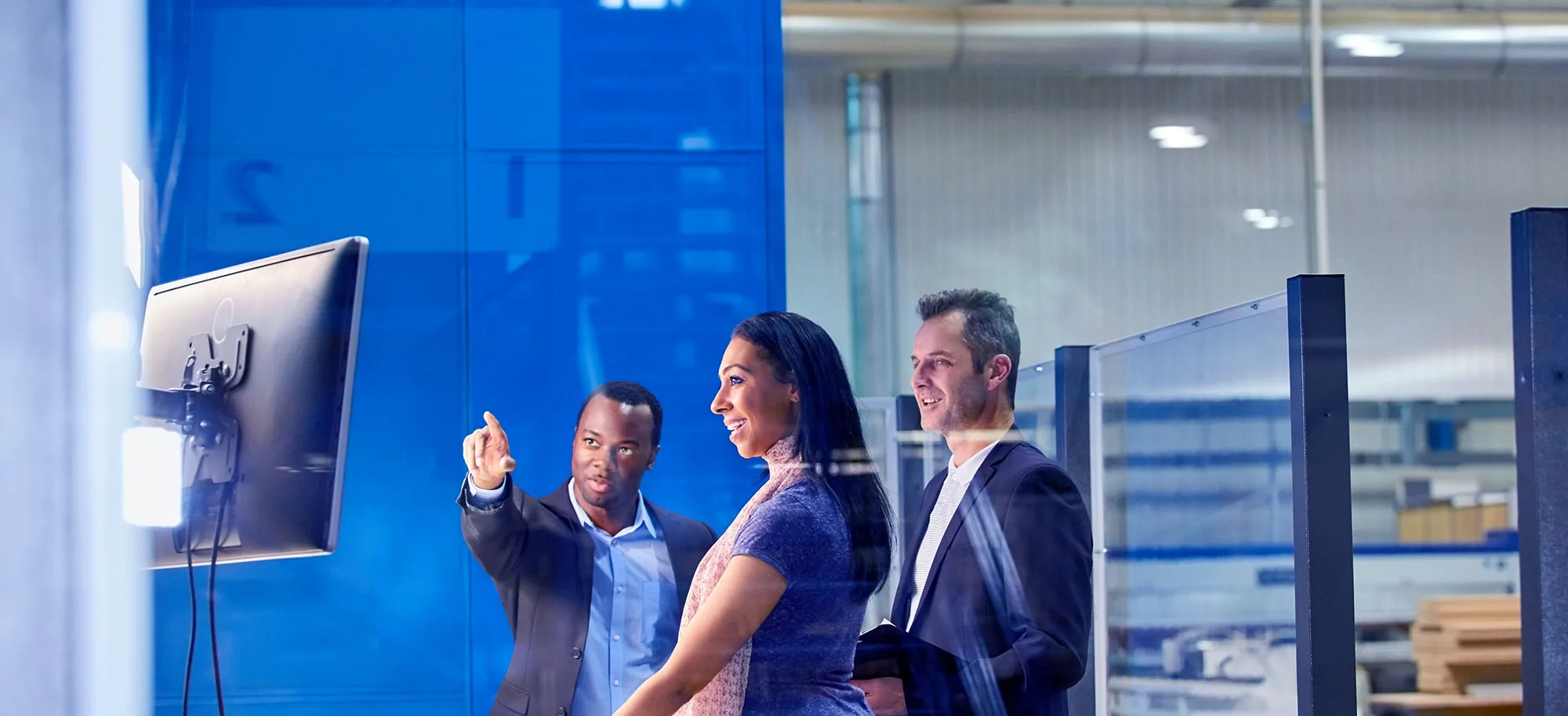 Technology team working together looking at a television screen in an office