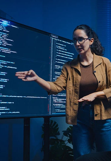 A woman pointing to a line of code on a monitor with a male coworker