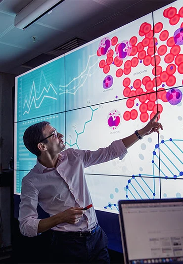 A man pointing to a healthcare graphic on a projecter with his team
